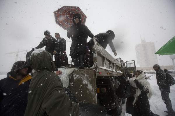 Israeli soldiers help stranded passengers off of an army truck to a temporary shelter after they had to leave their vehicles because of heavy snowfall in Jerusalem