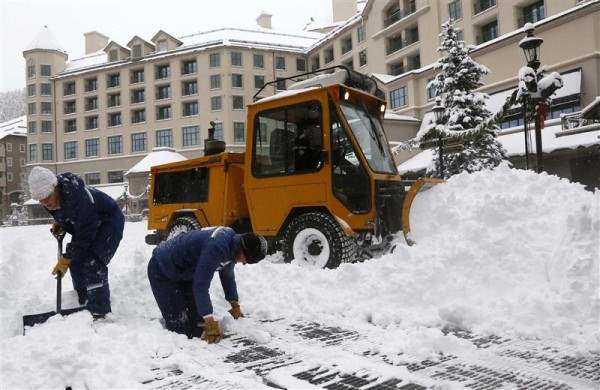 Workers clear snow off an ice skating rink in Beaver Creek