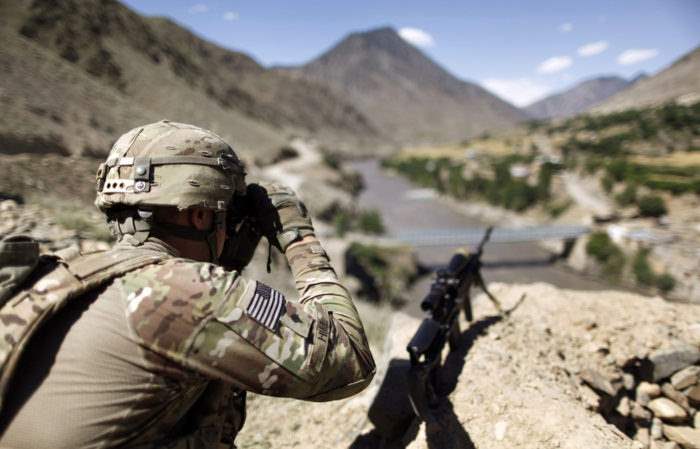 A soldier from the U.S. Army scans across the border at houses in Pakistan during a patrol near Dokalam village