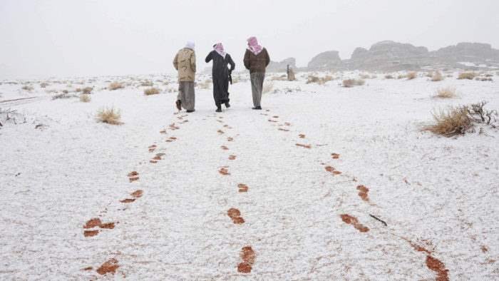 Saudi men walk as their footprints are seen after a snowstorm in Alkan village, west of Saudi Arabia December 13, 2013.  REUTERS/Mohamed Alhwaity (SAUDI ARABIA - Tags: ENVIRONMENT TPX IMAGES OF THE DAY)