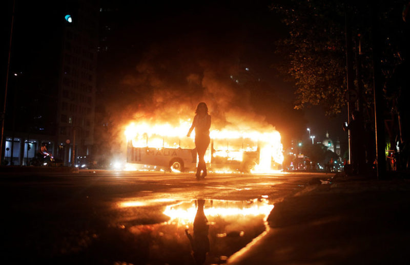 Женщина и горящий автобус в Бразилии.