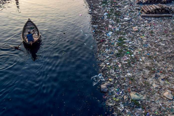 Мужчина проплывает мимо пластикового мусора