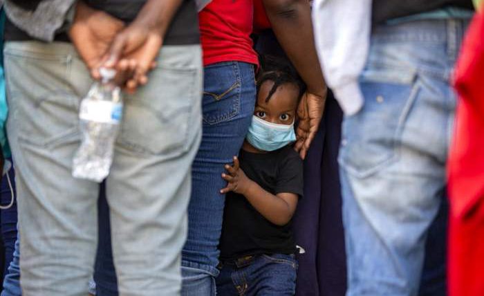 Ребенок стоит в очереди с гаитянами